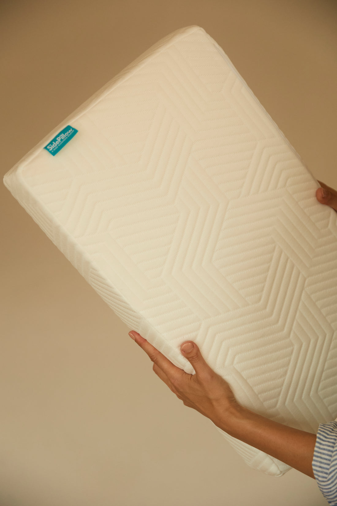 sidepillow kussen sfeerfoto, kussen in handen met muur op achtergrond