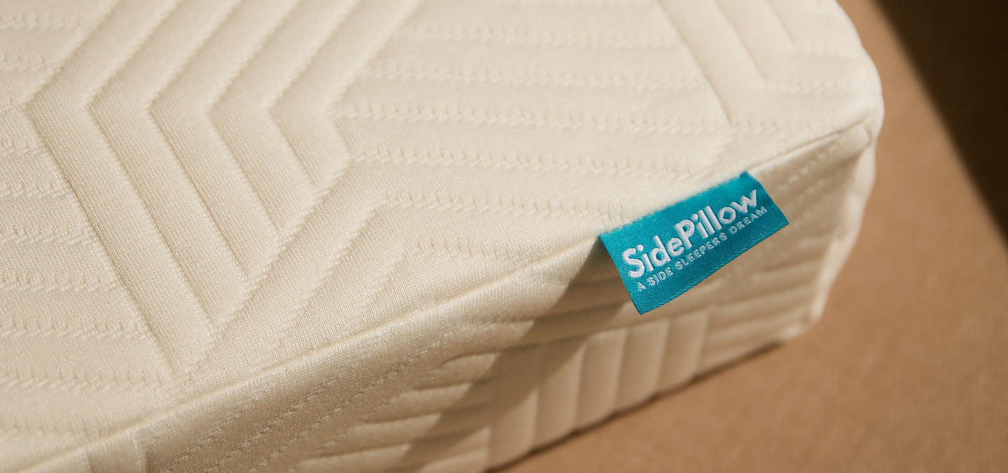 Close-up van de hoek van het SidePillow kussen met turquoise merklabel