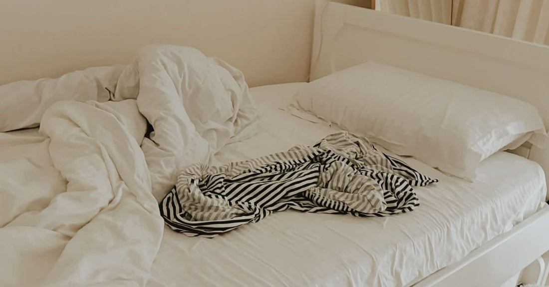 Onopgemaakt bed met omgewoelde dekens