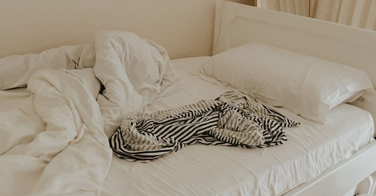 Onopgemaakt bed met omgewoelde dekens