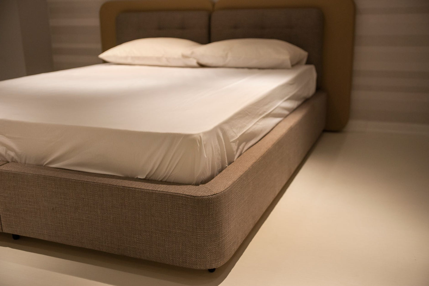 Hoek van een bed met een dikke matras en strak wit hoeslaken