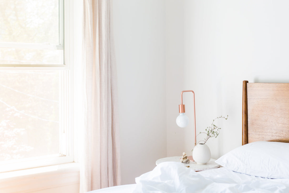 Minimalistische slaapkamer met wit hoofdkussen en koperen lamp