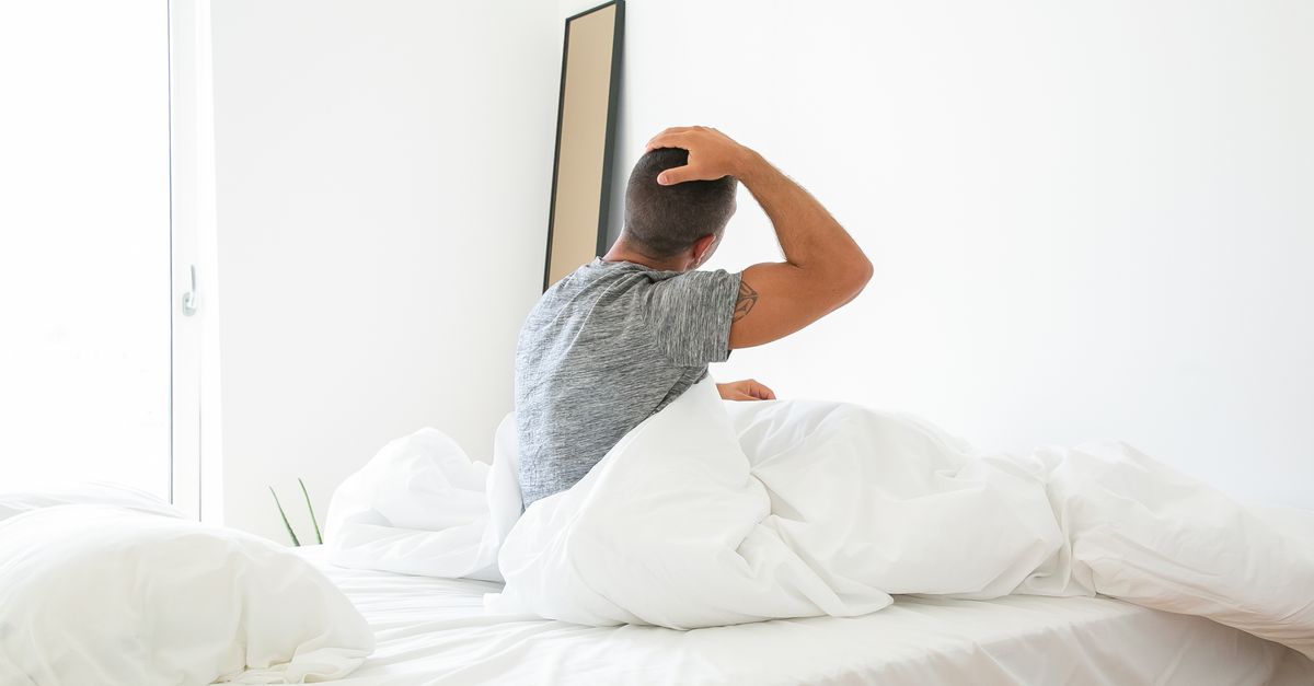 Man zit op de bedrand en rekt zich uit na het wakker worden