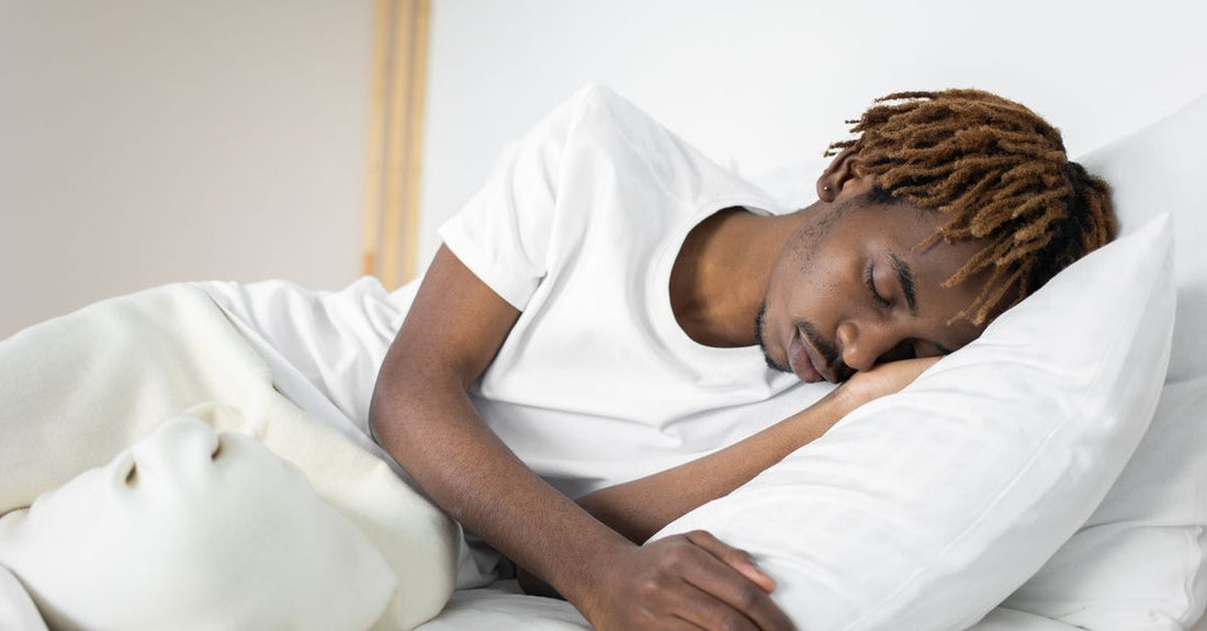 Man slaapt op zijn zij met zijn arm om een wit hoofdkussen