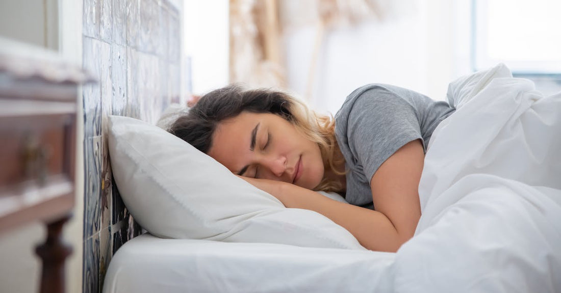 Vrouw ligt op haar zij met haar hoofd op een wit kussen