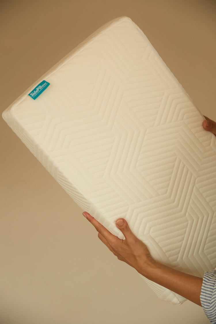 sidepillow kussen sfeerfoto, kussen in handen met muur op achtergrond